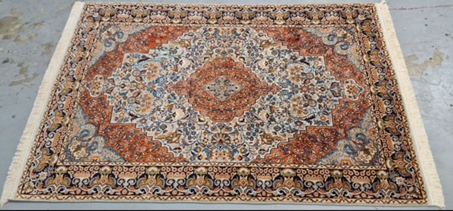 Le même tapis persan après retissage : le trou a disparu, le médaillon et les bordures sont à nouveau complets