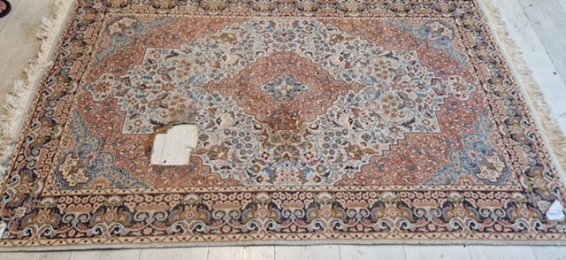 Tapis persan à médaillon présentant un trou en plein champ, avant restauration à l'atelier