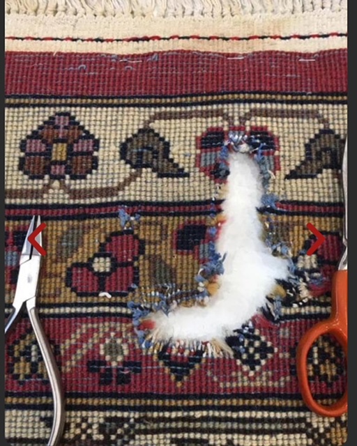 Trou de mite en cours de réparation : le bourrelet est reconstitué à la main au cœur du motif, ciseaux et pince posés sur le tapis
